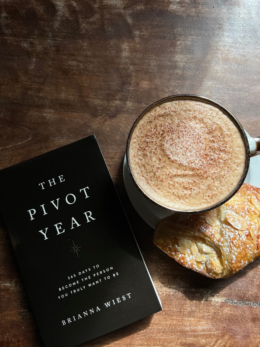 The Pivot Year beside a coffee and pastry on a café table