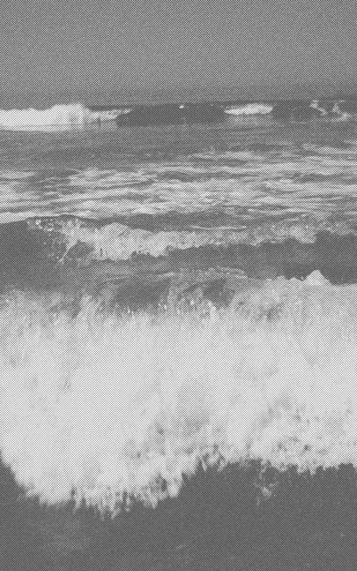 Black-and-white photograph of successive ocean waves breaking into white foam.